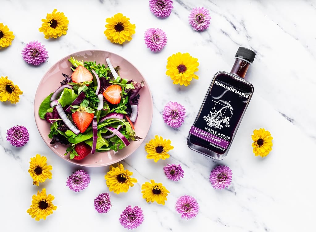 Elderberry Infused Maple Syrup with a plate of Salad and fresh flowers