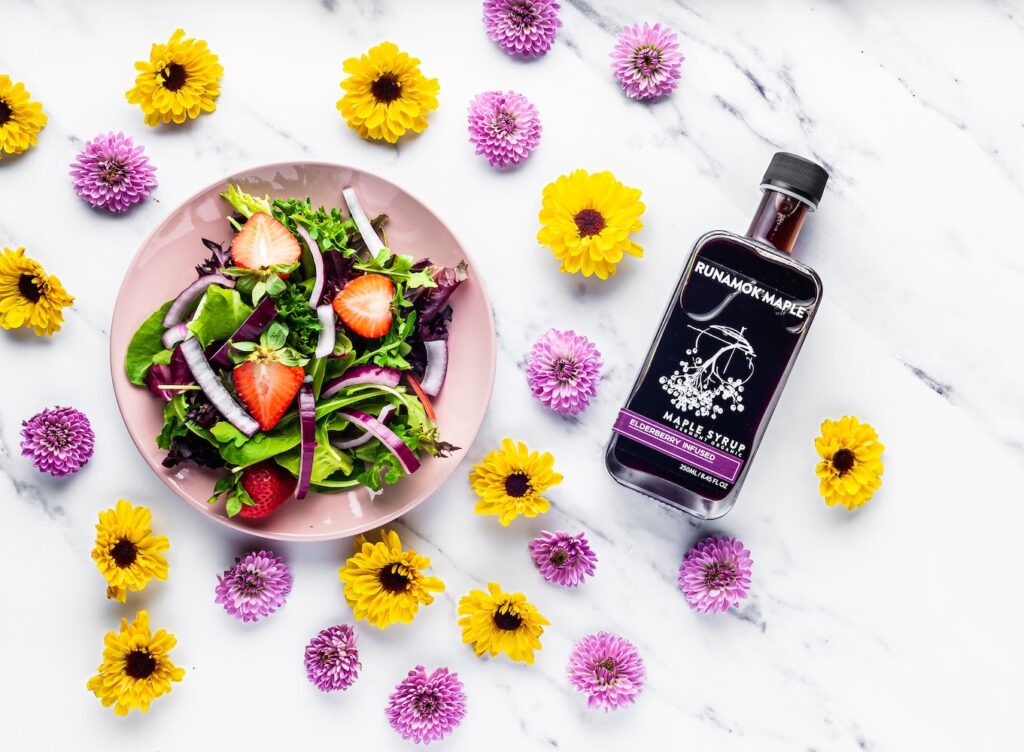 Elderberry Infused Maple Syrup with a plate of Salad and fresh flowers